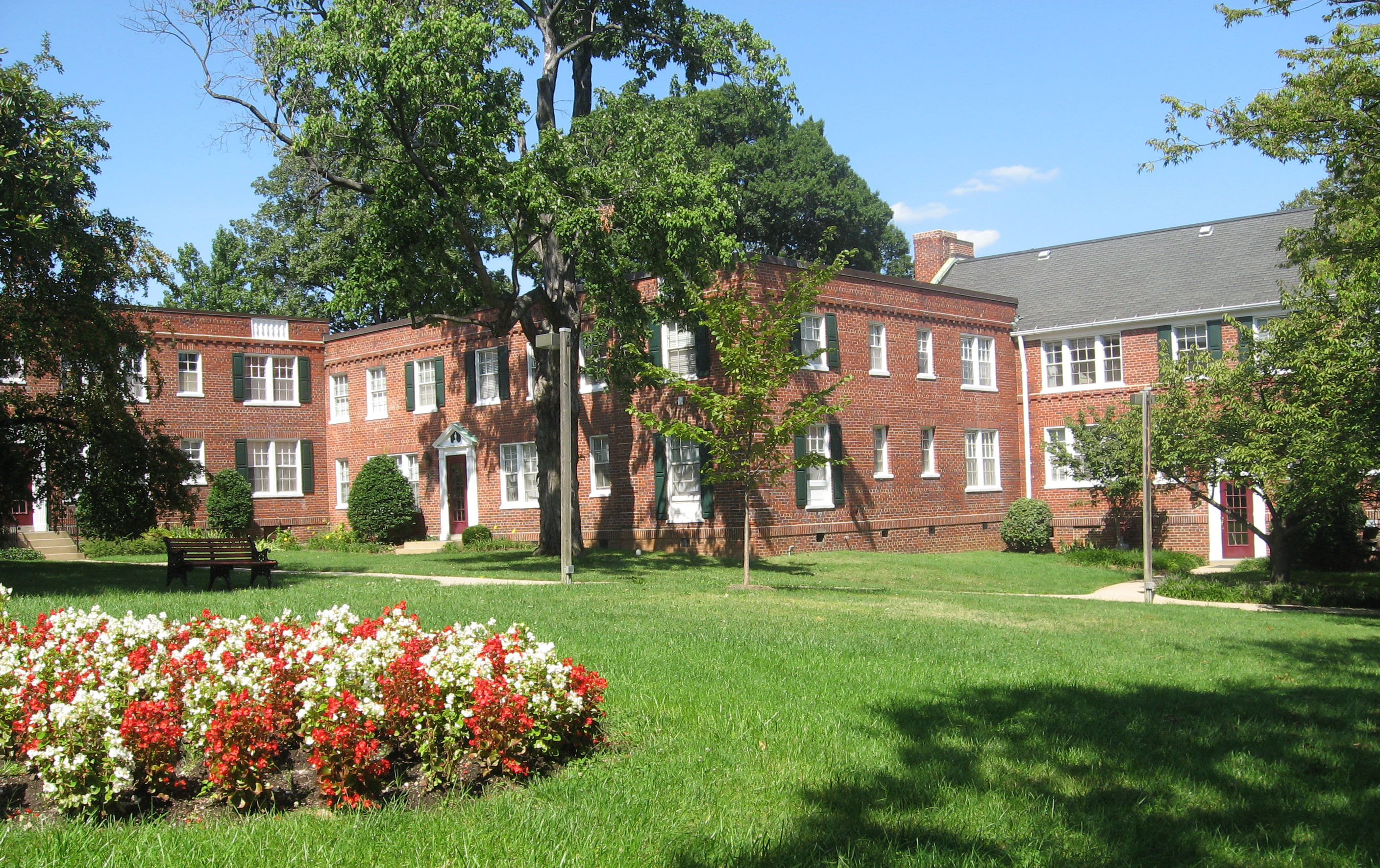 Multi level red brick building in background with lawn and flowers in foreground